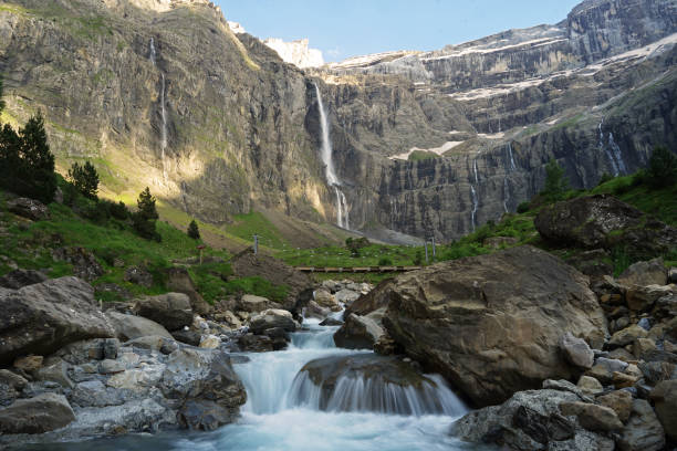 Cirque de Gavarnie beautiful waterfall with river underneath high cliffs, Pyrenees Mountains, France Cirque de Gavarnie beautiful waterfall with river underneath high cliffs, Pyrenees Mountains, France gavarnie stock pictures, royalty-free photos & images