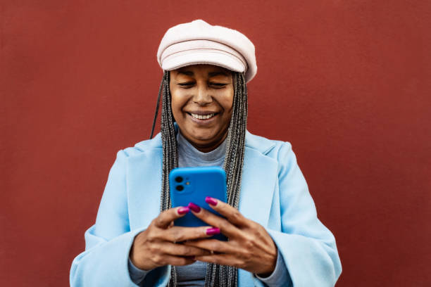 Senior African woman having fun using mobile smartphone outdoor