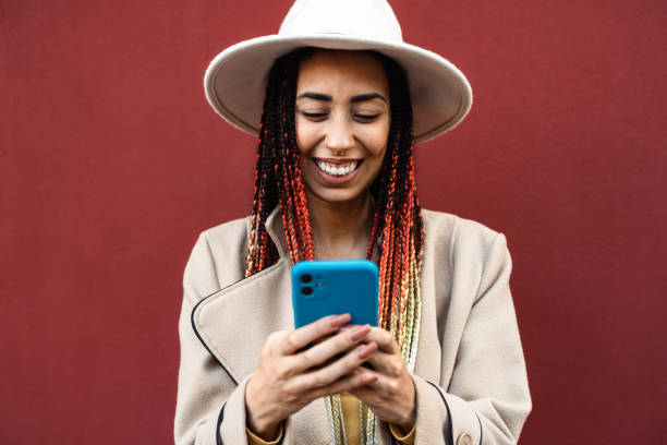 istock Happy young African girl having fun using mobile smartphone outdoor 1460237963