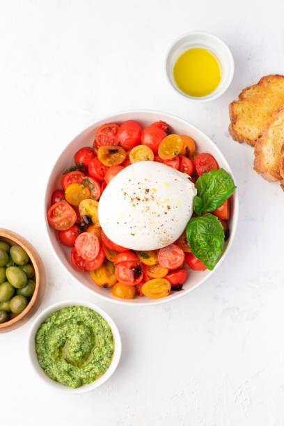 istock Farmer Italian soft cheese mozzarella di bufala campana served with fresh basil and red and yellow cherry tomatoes, croutons, homemade pesto, olives. Healthy Italian summer food, white background 1460238185