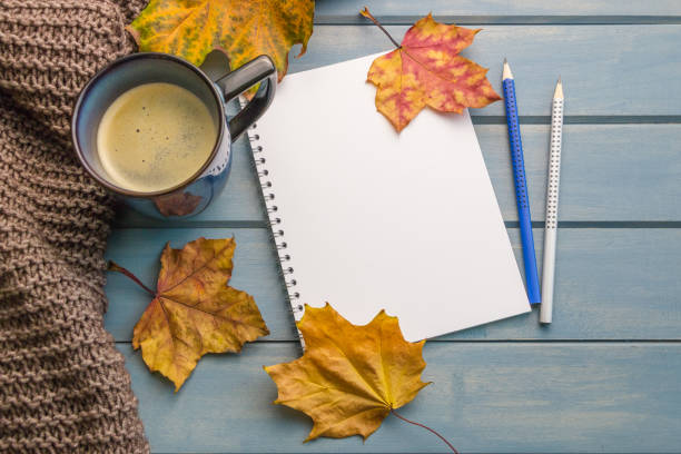 istock Autumn background. Composition with autumn leaves, blank notebooks, a cup of coffee on a blue wooden table 1460239653