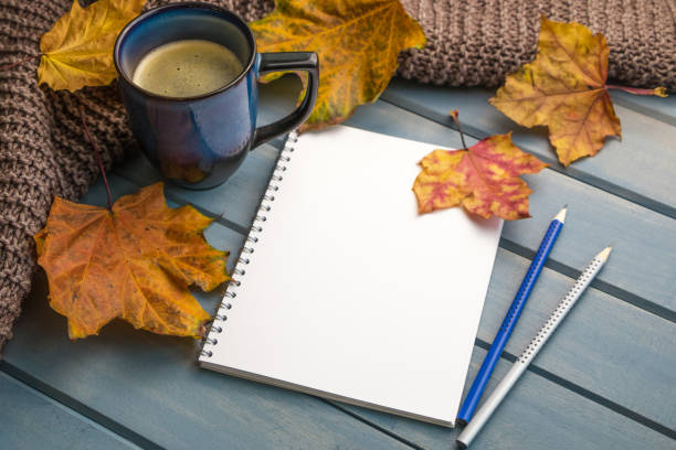 istock Autumn background. Composition with autumn leaves, blank notebooks, a cup of coffee on a blue wooden table 1460239729