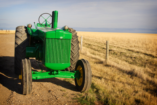 Sunlit vintage diesel tractor restored & freshly painted, on prairie Canadian farm.