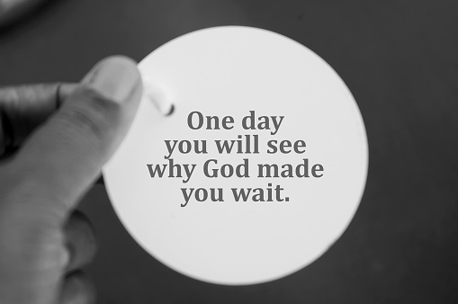 Spiritual inspirational quote - One day you will see why God made  you wait. With person holding white circle tag price paper in hand on black and white background. Spirituality and religious concepts. Patience and believe in God concept.