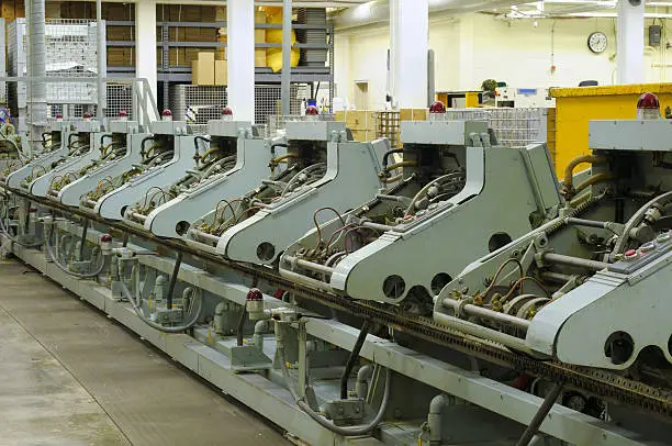 Row of stitching machines for binding booklets in a publishing house