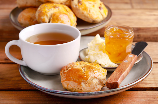 Homemade scones served with butter and marmalade and cup of tea