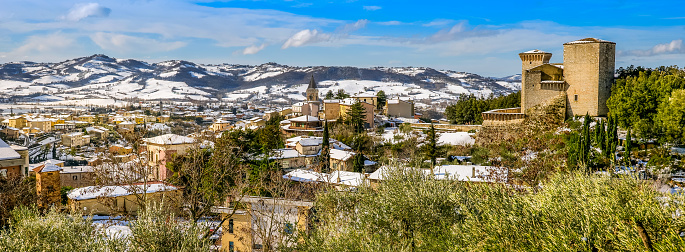 A splendid winter scenery between snow-capped mountains and hills of the medieval village of Gualdo Tadino in Umbria, central Italy. An important city since Roman times, Gualdo Tadino rises along the ancient consular Via Flaminia, traced by the Romans. Its history runs throughout the Middle Ages and, despite having been partially destroyed and sacked numerous times and placed under the dominion of Perugia, this ancient Umbrian center still retains its medieval charm. The Umbria region, considered the green lung of Italy for its wooded mountains, is characterized by a perfect integration between nature and the presence of man, in a context of environmental sustainability and healthy life. In addition to its immense artistic and historical heritage, Umbria is famous for its food and wine production and for the high quality of the olive oil produced in these lands. Image in 65x24 ratio and high definition quality.