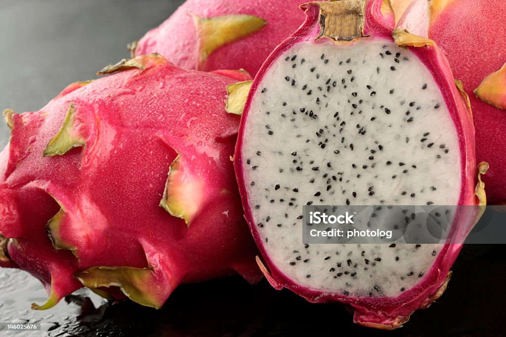 Dragon fruit whole and sliced in half on black background Dragon fruits with half photographed on black background Arrangement Stock Photo