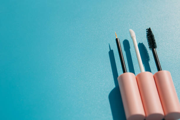 istock pink brushes for cosmetics, mascara, liquid lipstick, eyeliner, lip gloss on a blue background, copy space 1460260456
