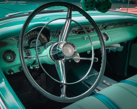 The metal interior and steering wheel of a fifties classic car.