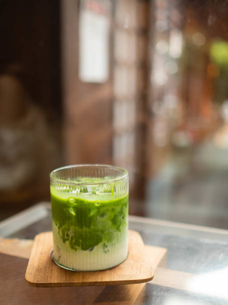 Image of a mug of matcha green tea mix milk on a brown wooden coaster. stock photo