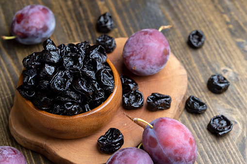 Black pile of prunes from a large number of ripe plums, a pile of prunes on a wooden table in the kitchen close-up