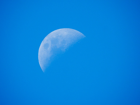 Earth's moon on a cloudless day viewed from Sydney in the southern hemisphere, on the afternoon of 28 January 2023.  Black has been added to the light settings to make the sky appear a darker blue.