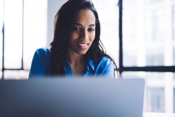 istock Smiling black woman reading information on laptop screen 1460266250