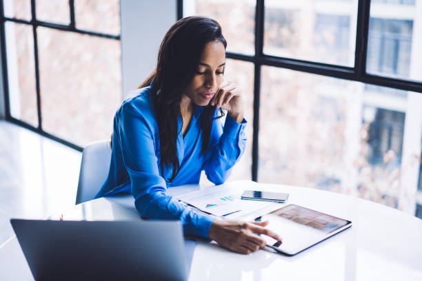 istock Concentrated black woman working touching screen of tablet at table 1460266276