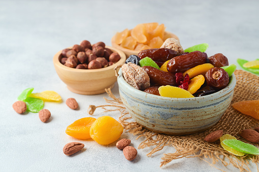 Dried dates, fruits and nuts in bowl over rustic background.