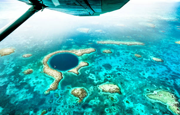Aerial panoramic view of The Great Blue Hole - Detail of Belize coral reef from airplane excursion - Wanderlust and travel concept with nature wonders on azure vivid filter stock photo