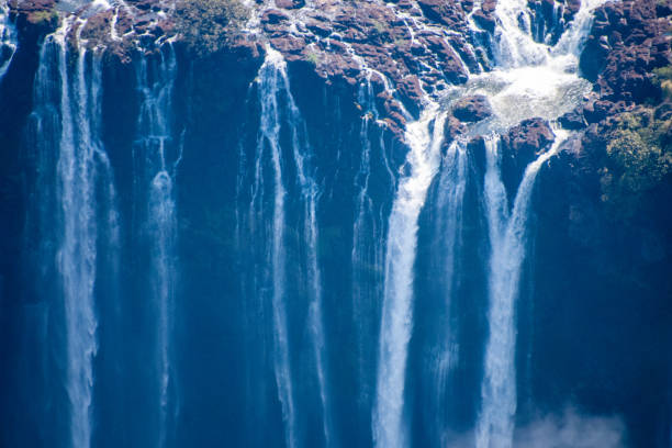 A dramatic view of Victoria Falls cascading into a misty gorge with lush riverbank trees. This iconic African waterfall captures nature’s power, scale, and beauty.