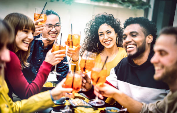 Trendy friends toasting spritz cocktail at bar restaurant - Life style concept with young people having fun together sharing drinks on happy hour at garden party - Vivid contrast filtered color tones stock photo