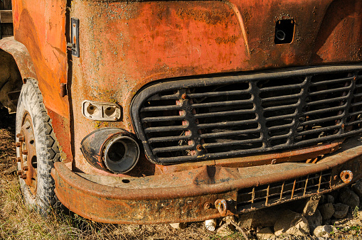 An old blue tractor stands in a farmyard.