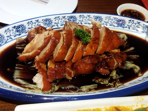 Cutting the roast duck and oranges on a black slate board. horizontal view from above