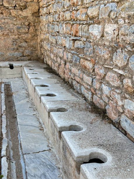 row of medieval toilets in the run ins of the city of ephesus, turkey - toilet public restroom ephesus history imagens e fotografias de stock