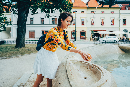 Hungry tourist woman rinsing an apple outside at summer travel in Slovakia