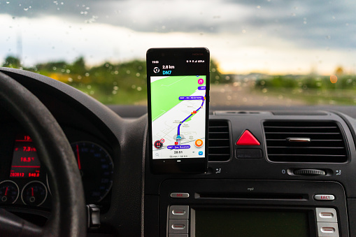 Using waze maps application on smartphone on car dashboard, Bucharest, Romania, 2023