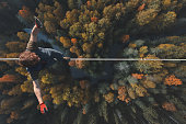 Highline over the forest. Rope walker walks on a rope at high altitude. Drone view. Slackline theme