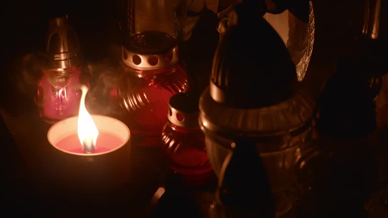 Cemetery grave candle lanterns illuminated by night.