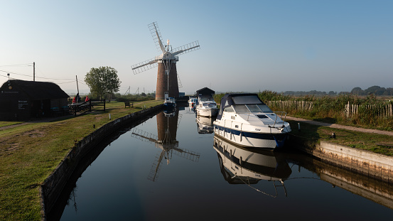 Norfolk windpump with waterway boats and reflections ii. Horsey Mill, August 2019