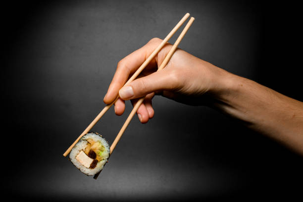 istock hand accurate holds unagi sushi roll with smoked eel with chopsticks on dark background 1460295275
