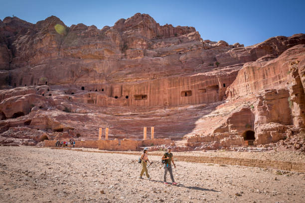 Petra, Jordan - November 19, 2018 : On this magnificent archaeological site declared a UNESCO World Heritage Site, there is an ancient Nabataean city where the buildings are carved out of the red and pink sandstone mountains, fantastic engineering achievements and marvelously well preserved. Many tourists admire these remains and bedoins offer transport services on their donkeys, camels, carts for people who want to see the attractions without having to walk. On the photo, tourists are enjoying the beauty of this magnificent site near the theater.  The site was chosen as one of the New Seven Wonders of the World. Needless to say, this is the most popular tourist site in the country.
