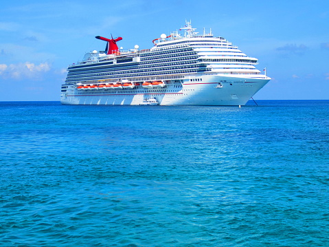 Summer of 2015- the beautiful Carnival Breeze cruise ship sits in the beautiful blue Caribbean waters of Grand Cayman while tenders bring passengers to land.