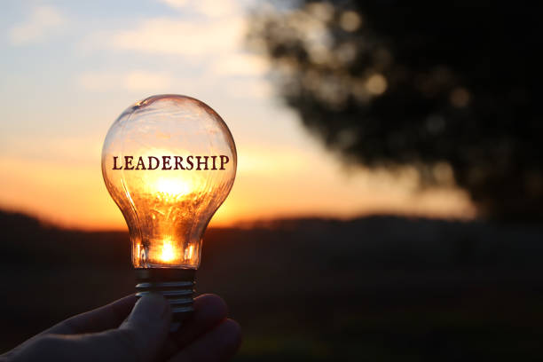 istock Hand holding light bulb with the text leadership in front of the bright sun 1460299003