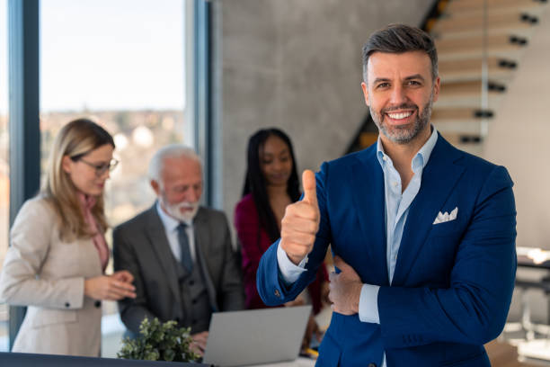 istock Modern stylish corporate leader, successful CEO executive manager in suit posing with thumb up showing a sign of success 1460300486