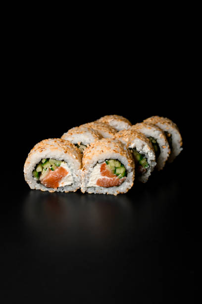 blick auf sushi-rollen california mit geräuchertem lachs, frischkäse, gurken, sesam auf dunklem hintergrund. - japanese cuisine appetizer gourmet caviar stock-fotos und bilder