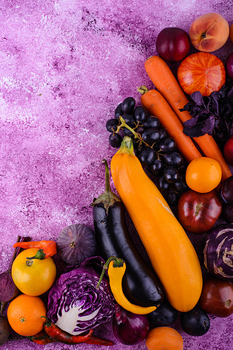 Assortment of fresh purple and yellow vegetables on violet background