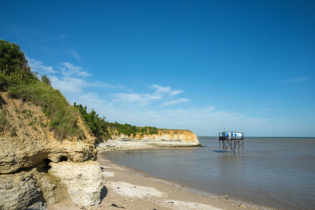 Ile Madame beach Charente-Maritime, France with eroded coastline and fishing huts on stilts in the sea near La Rochelle