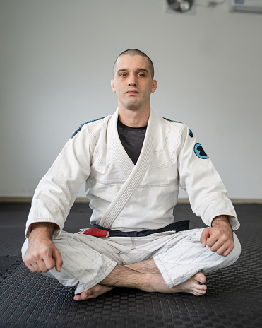 brazilian jiu jitsu BJJ black belt instructor professor at the academy sitting on the tatami mats
