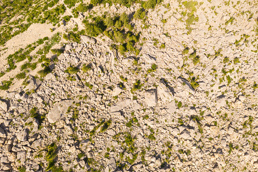 Drone pint of view of mountain rock slide and hiking path through it during summer day.