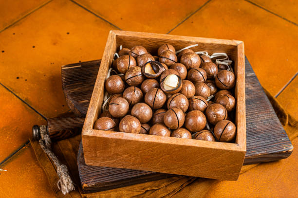 istock Macadamia natural nuts in a box. Orange background. Top view 1460328126