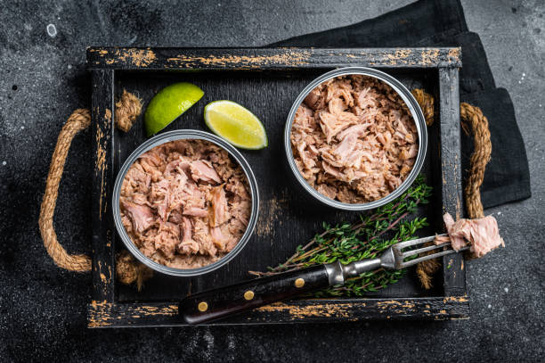 istock Open Can with Preserved tuna fillet meat. Black background. Top view 1460328244