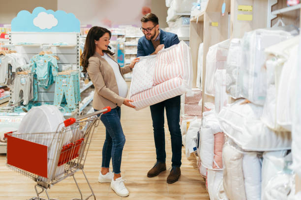Young couple in baby shop Attractive middle age couple enjoying in buying clothes and appliances for their new baby. Heterosexual couple in baby shop or store. Expecting baby concept. baby boutique stock pictures, royalty-free photos & images
