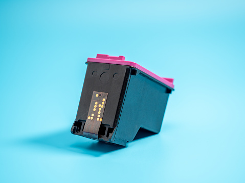 Cartridge with paint for the printer on a blue background. Close-up.