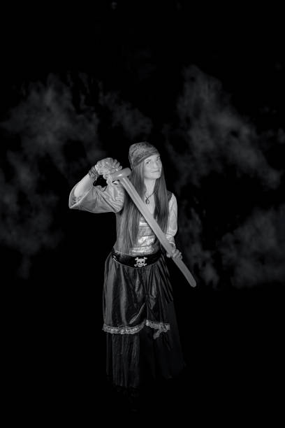 woman with long hair dressed as a pirate in a red suit and with a yellow balloon in the shape of a sword in her hand and on a black background photography of party events
