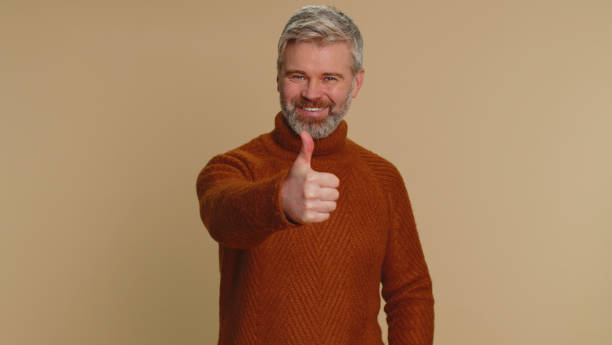 istock Middle-aged man raises thumbs up agrees or gives positive reply recommends advertisement likes good 1460355121