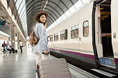 Young woman with a big suitcase traveling by a train