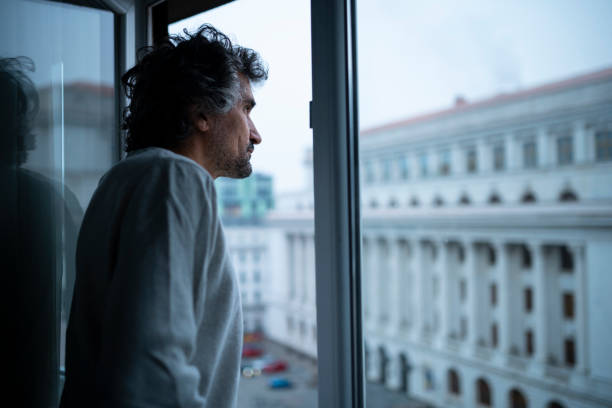 istock Urban lifestyle. Man looks from tall building window. 1460362988
