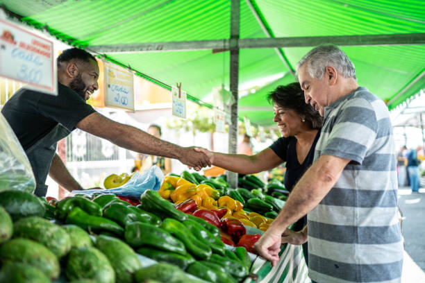 verkäufer begrüßt kunden auf einem straßenmarkt - farmers market stock-fotos und bilder